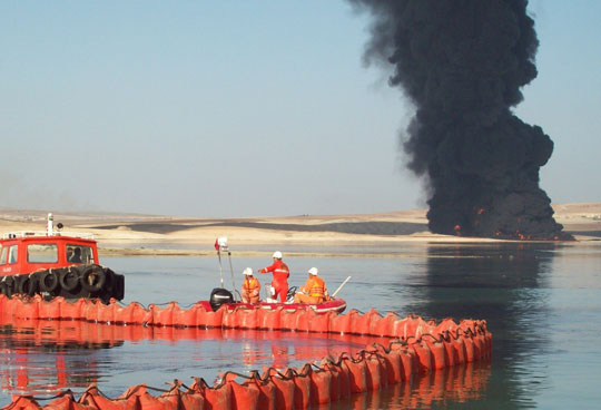 oil spill skimmer with tank on fire in background